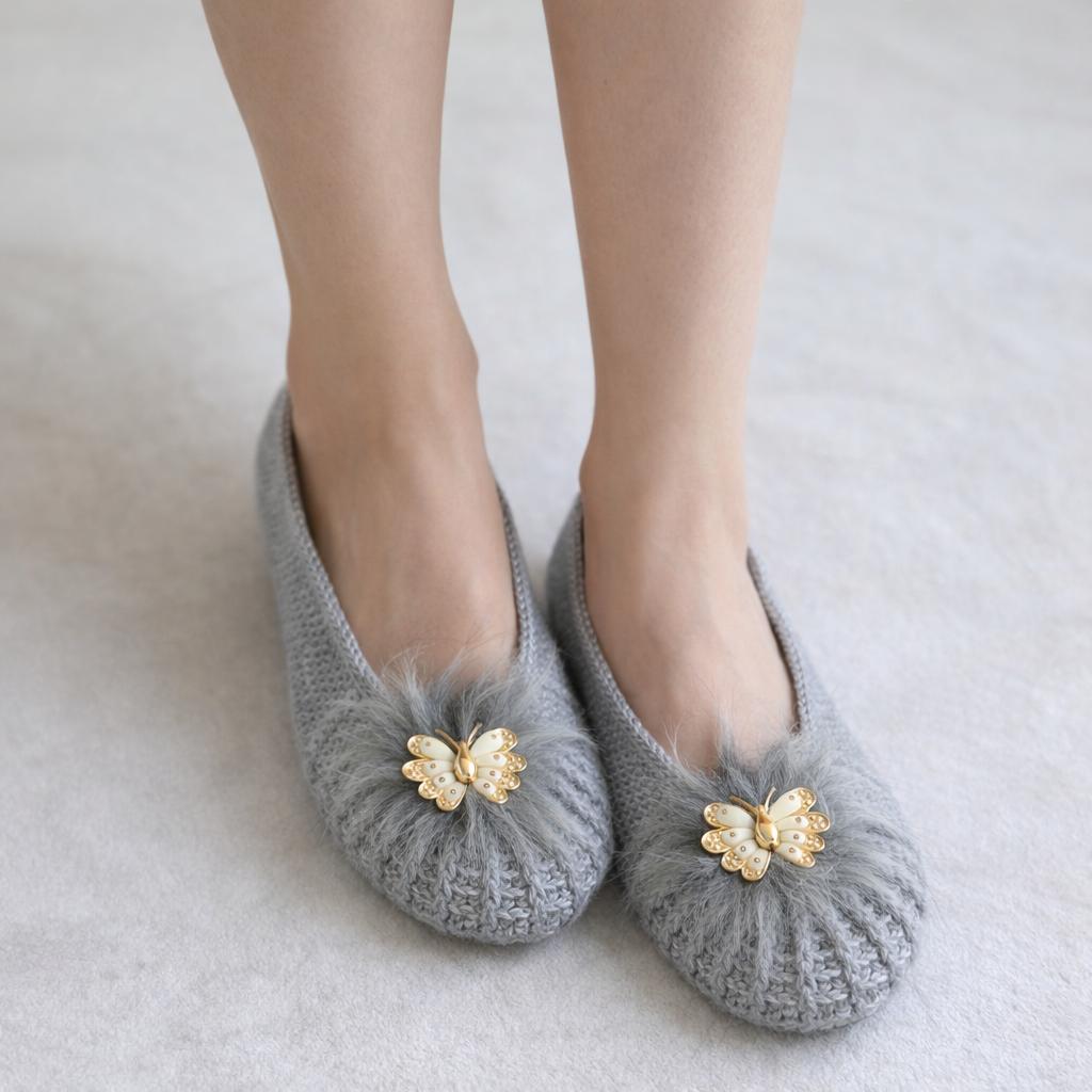 : Grey hand-knit ballet slippers with fluffy faux-fur pom and gold butterfly brooch